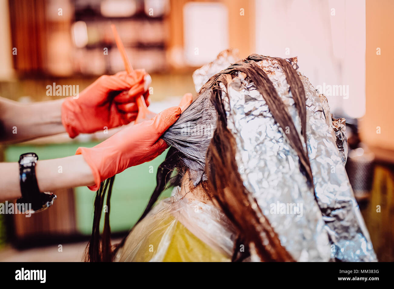 Woman in gloves is dying hair. hair dyeing. Toned image. Hair in foil Stock Photo