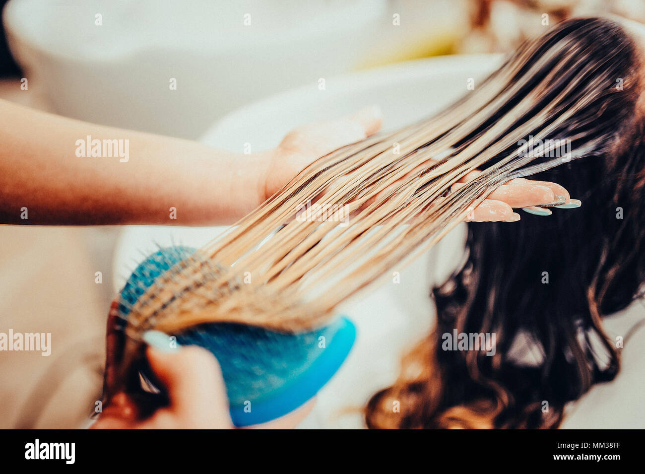 girl in a beauty salon. wash your hair, hair care, health. Toned image. Combing of washed hair with a special comb in the hairdresser's. Stock Photo