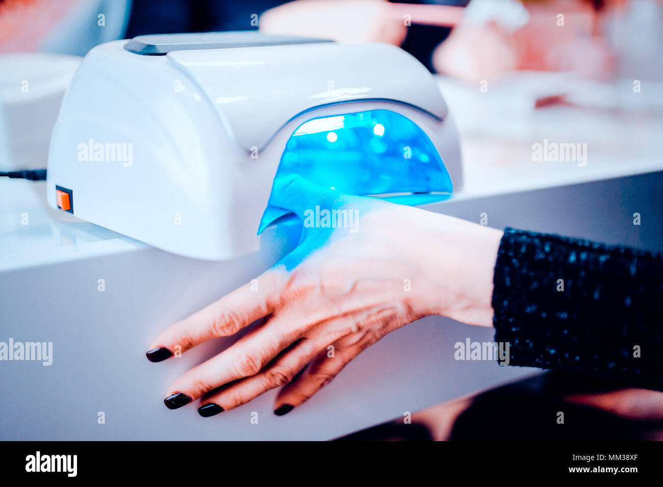 UV lamp to fix the gel coat on nails. the client dries the hand in a special lamp for complete drying of the manicure. Toned image. Stock Photo