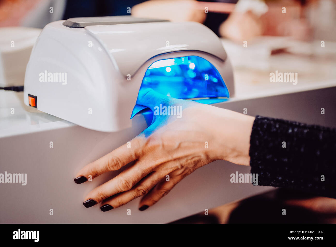 UV lamp to fix the gel coat on nails. the client dries the hand in a special lamp for complete drying of the manicure. Toned image. Stock Photo