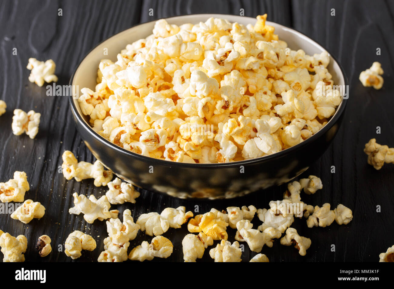 Cheddar cheese salted popcorn closeup in a  bowl on black table. vertical Stock Photo