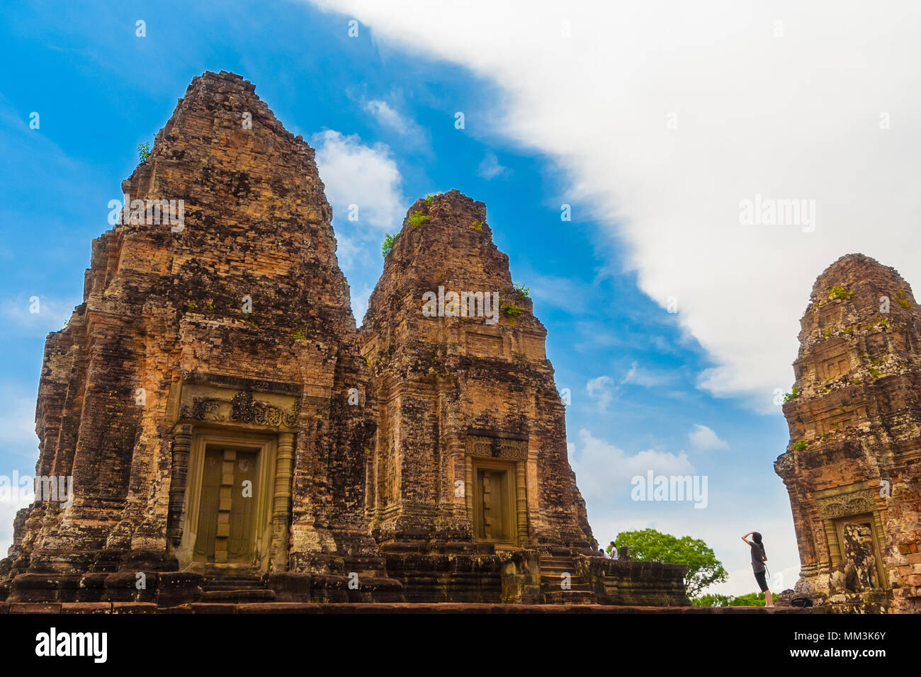 Great photo of a tourist looking up to two laterite brick towers of the inner sanctuary in Cambodia's East Mebon temple. Stock Photo
