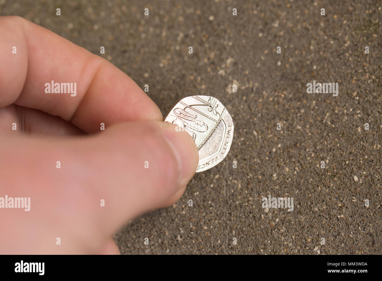 Posed picture of picking up a twenty pence piece from the ground. UK Stock Photo