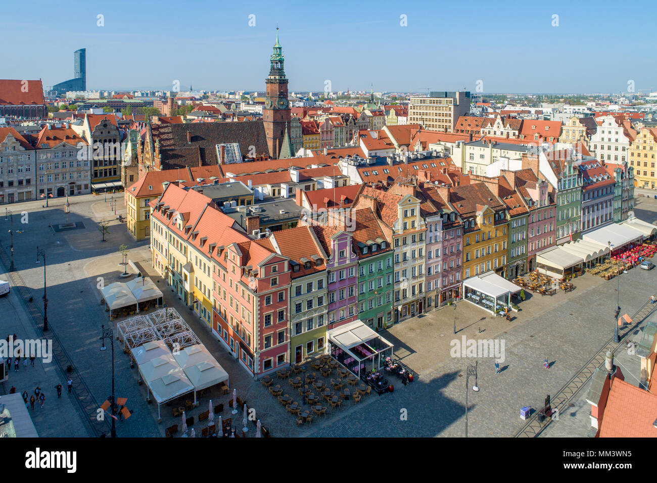 Poland, Wroclaw. Market Square (Rynek) with old historic tenements, gothic city hall and outdoor restaurants. Aerial view. Early morning. Stock Photo