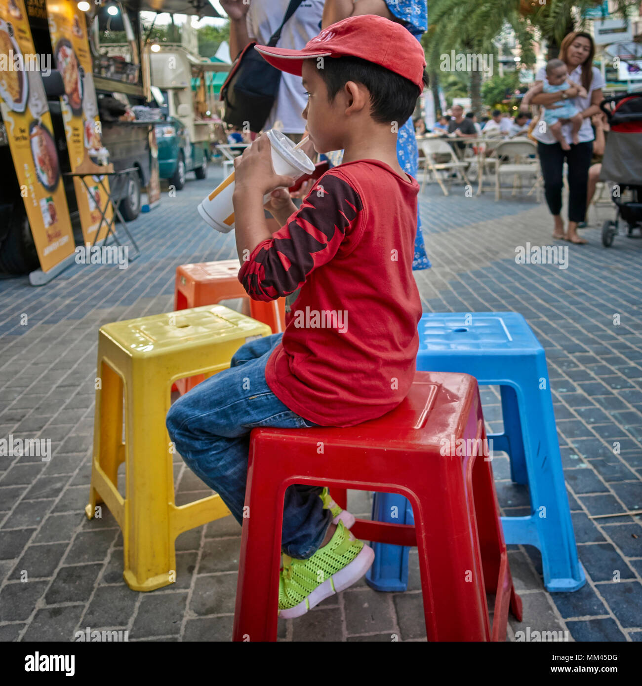Child alone and content with a soft drink. Thailand Southeast Asia Stock Photo