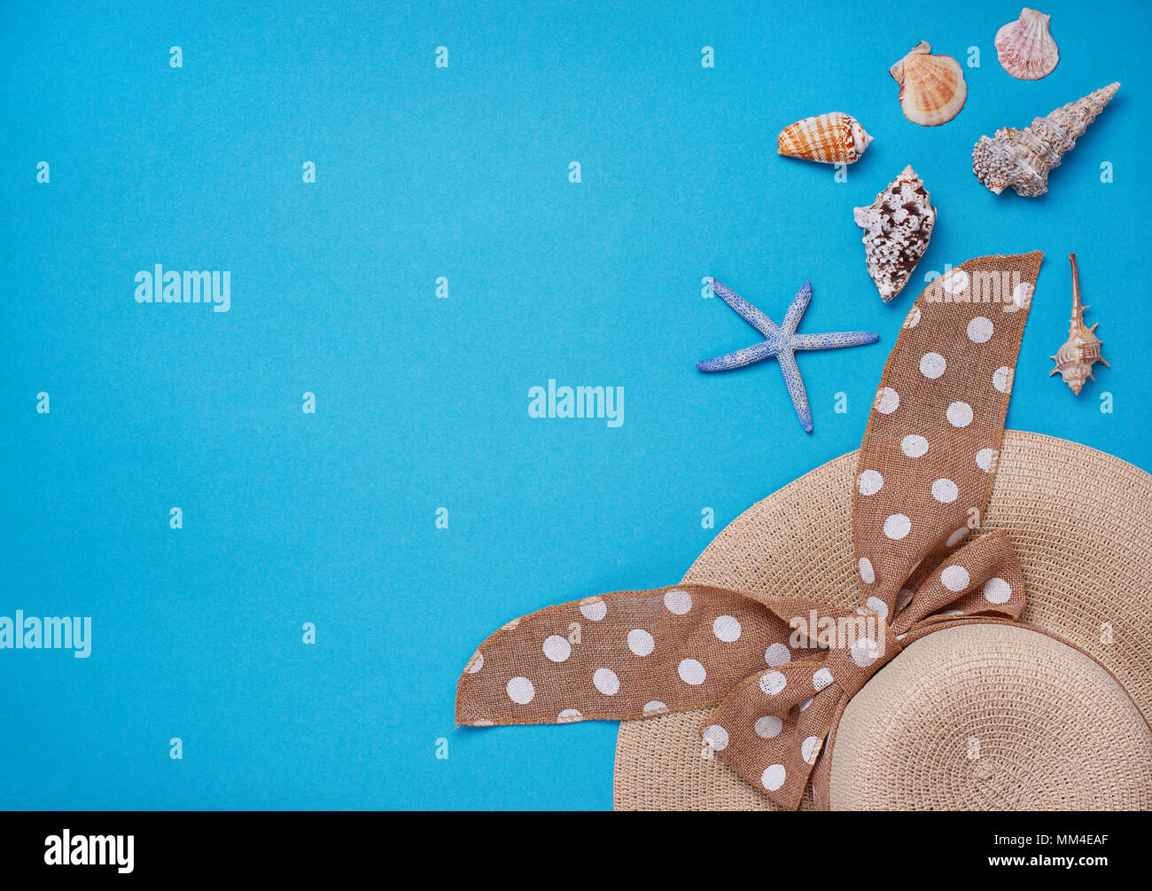Straw  hat and seashells on blue background Stock Photo
