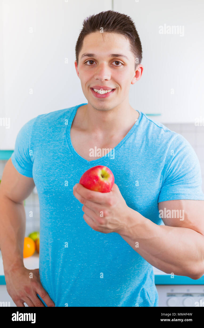 Healthy eating young man eat apple fruit in the kitchen portrait format