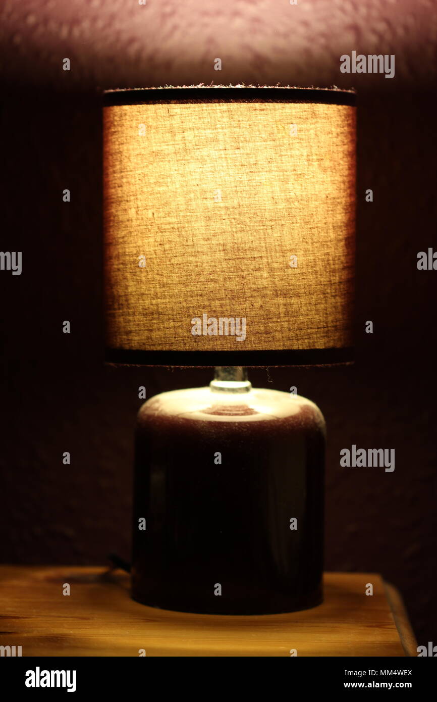 close up bed side table lamp on glowing in dark room at night Stock