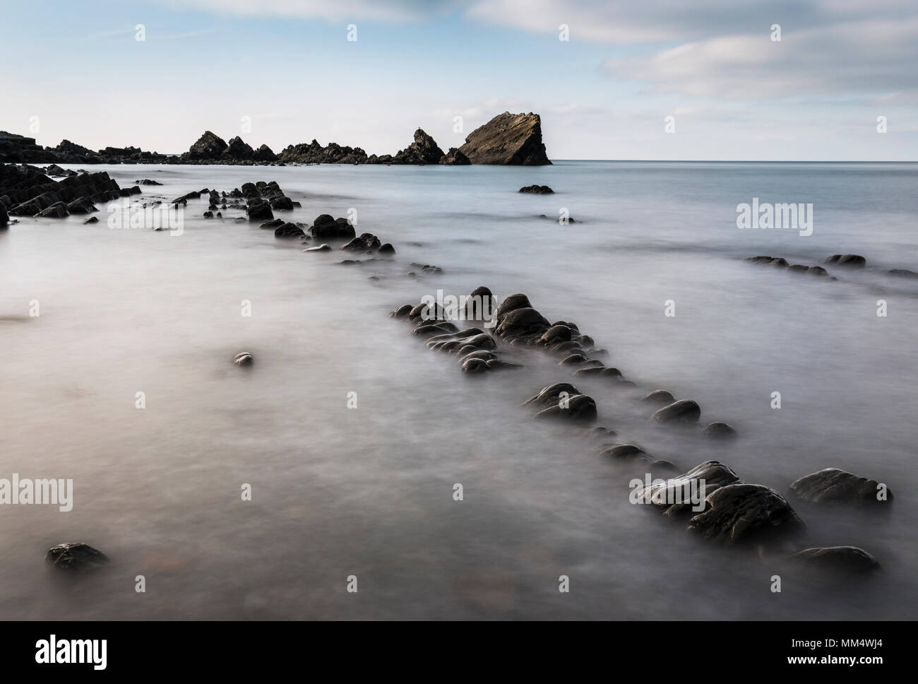 Lines of black rocks at low tide on south coast of England Stock Photo