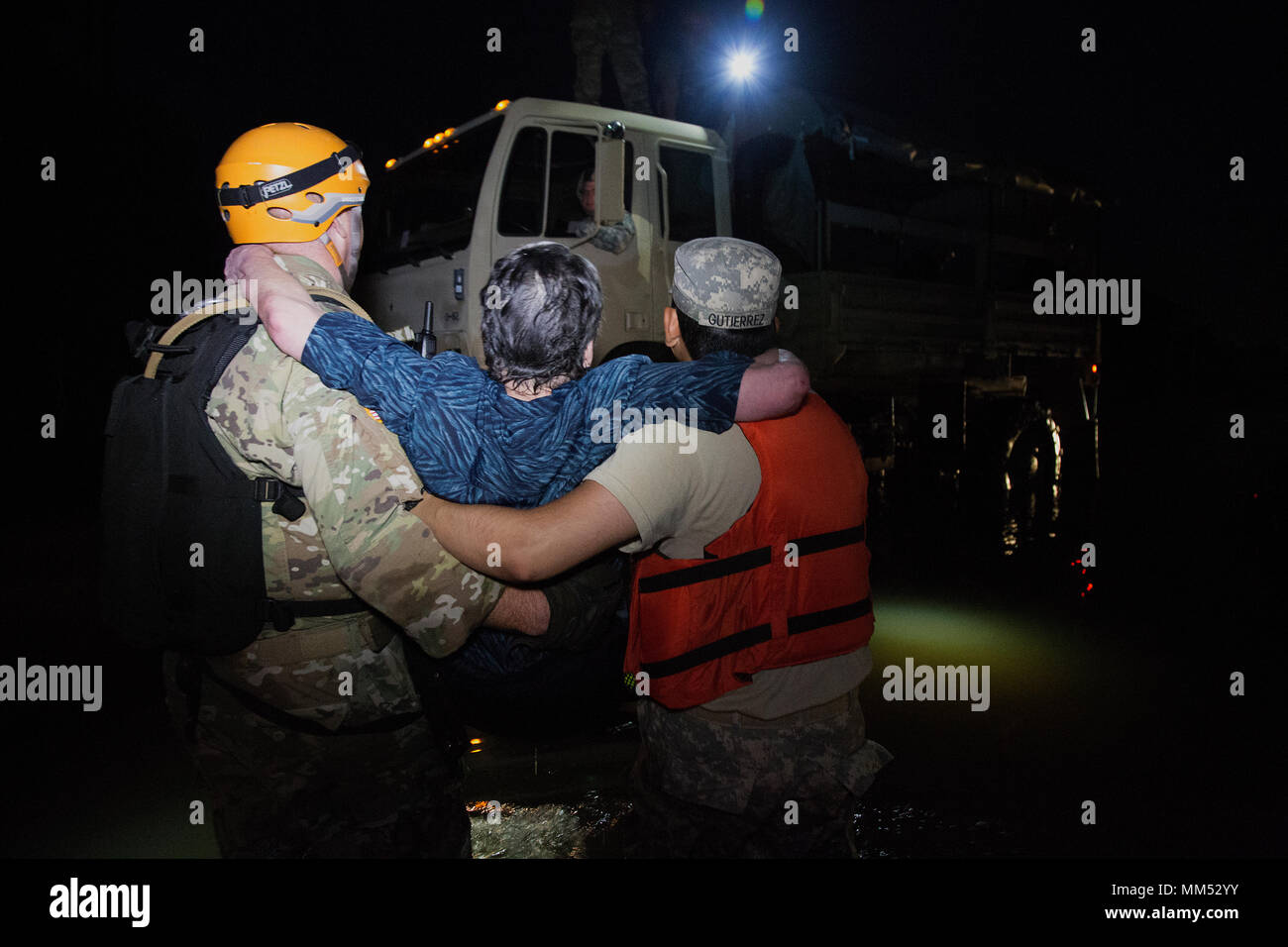 U.S. Army Sgt. Aaron Amos and Eric Gutierrez of the 1-124th Cavalry Squadron, Texas Army National Guard, carries a flood victim to safety in Orange, Texas, Sept. 4, 2017. The U.S. Military and relief agencies continue to assist in aiding those affected by Hurricane Harvey. (U.S. Army photo by Staff Sgt. Carl Greenwell) Stock Photo