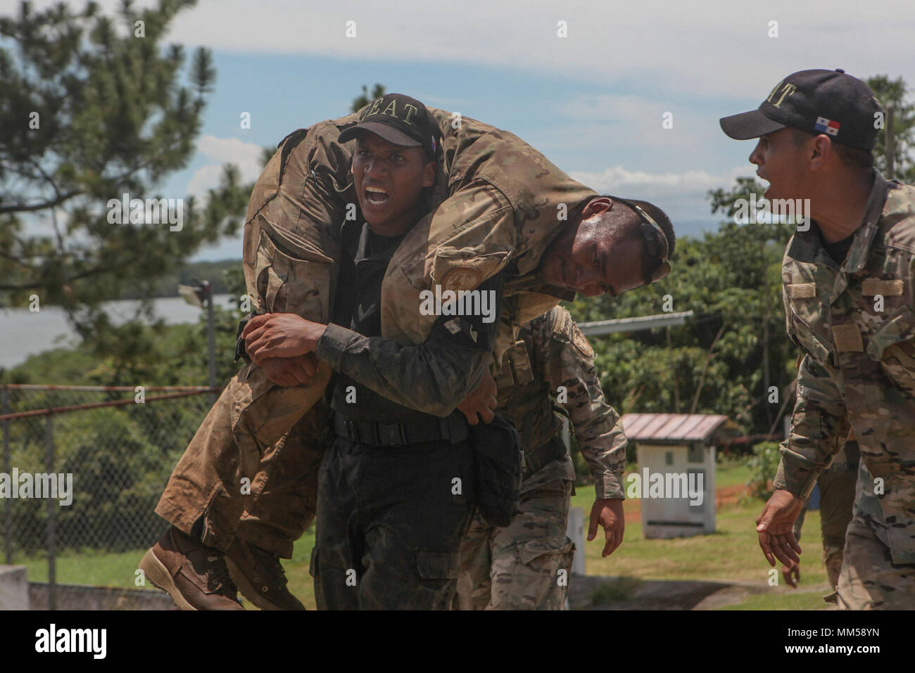 Panamanian Institutional Protection Service Cpl. Fernando A. Jaramillo, right, motivates Cpl. Jose A. Diaz, left, also assigned to ISP, while Diaz carries Cpl. Alexander Camero, an infantryman assigned to the Servicio Nacional Aeronaval, during a final exercise of a course conducted by U.S. Marines with Mobile Training Team One, Command Element, Special Purpose Marine Air-Ground Task Force - Southern Command, at Agustin Santos Vinda Base in Quebrada de Piedra, Panama, Aug. 31, 2017. The MTT conducted a three-week course with Panamanian service members consisting of basic infantry tactics, mark Stock Photo