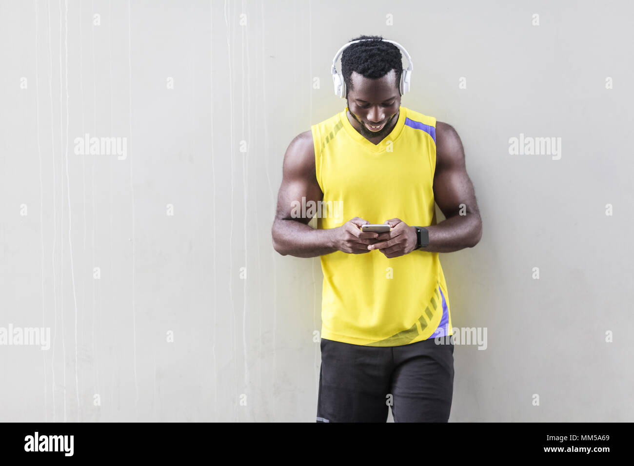dark skinned sporty man holding smart phone and chatting. Outdoor shot, morning. Spring or summer Stock Photo