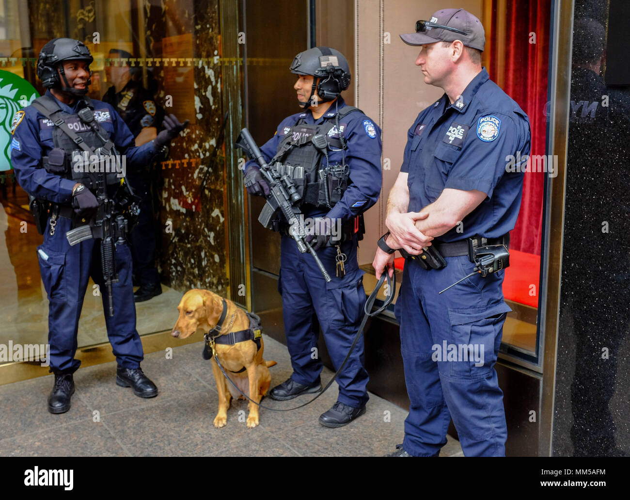 Police officers with automatic weapons and K9 guard the entrance to Trump Tower in New York City May 6, 2-18. Stock Photo