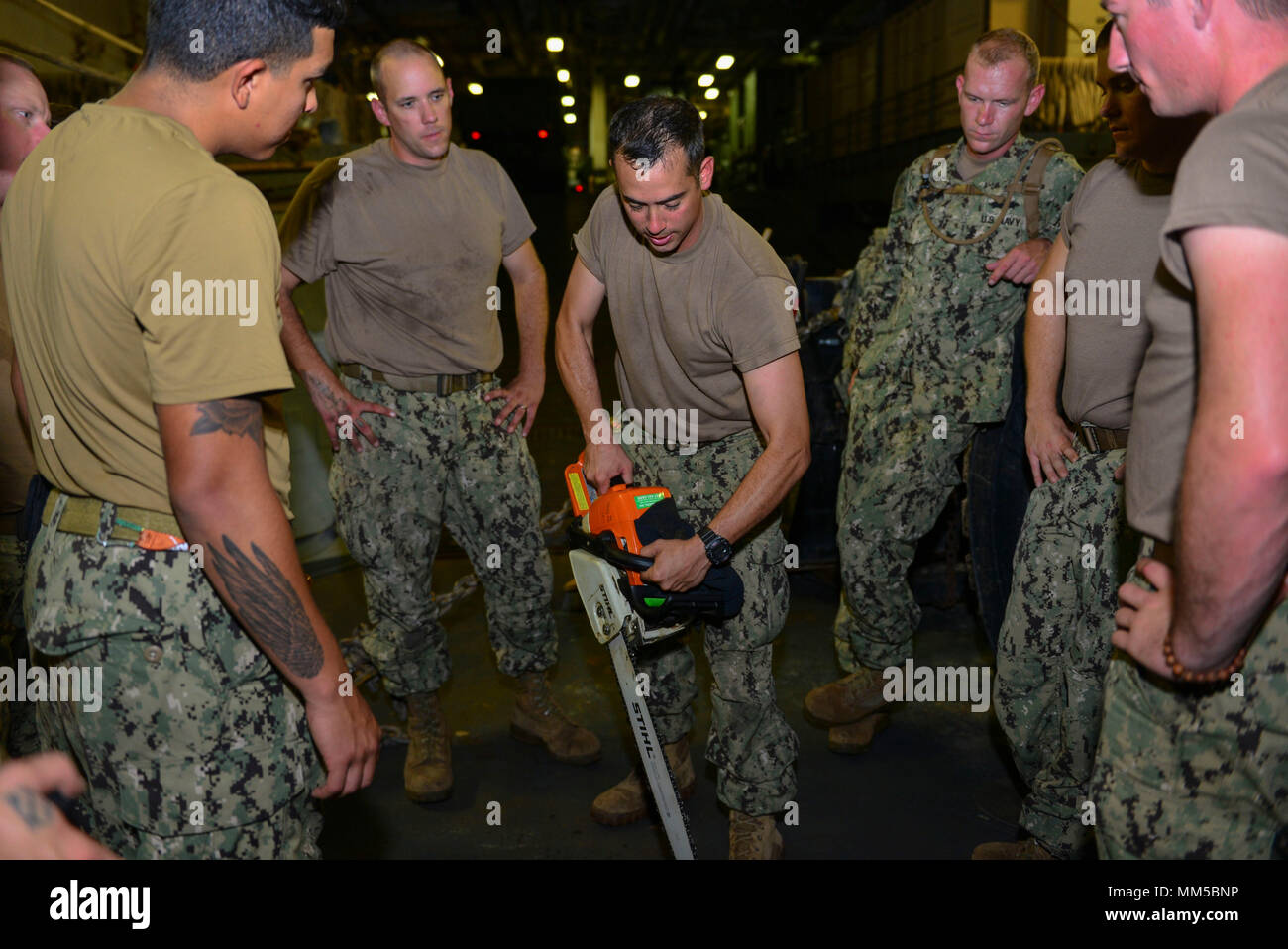 ATLANTIC OCEAN (Sept. 9, 2017) Equipment Operator 2nd Class Christopher Fleming, assigned to Assault Craft Unit (ACU) 2, gives training on chainsaw maintenance in the well deck of the amphibious assault ship USS Iwo Jima (LHD 7) in preparation for potential humanitarian relief efforts. The preparations ensure Iwo Jima is ready to respond to any requests to bolster Northern Command’s support of the Federal Emergency Management Agency assistance to federal, state and local authorities’ ongoing relief efforts in the aftermath of Hurricane Irma. (U.S. Navy photo by Mass Communication Specialist 3r Stock Photo