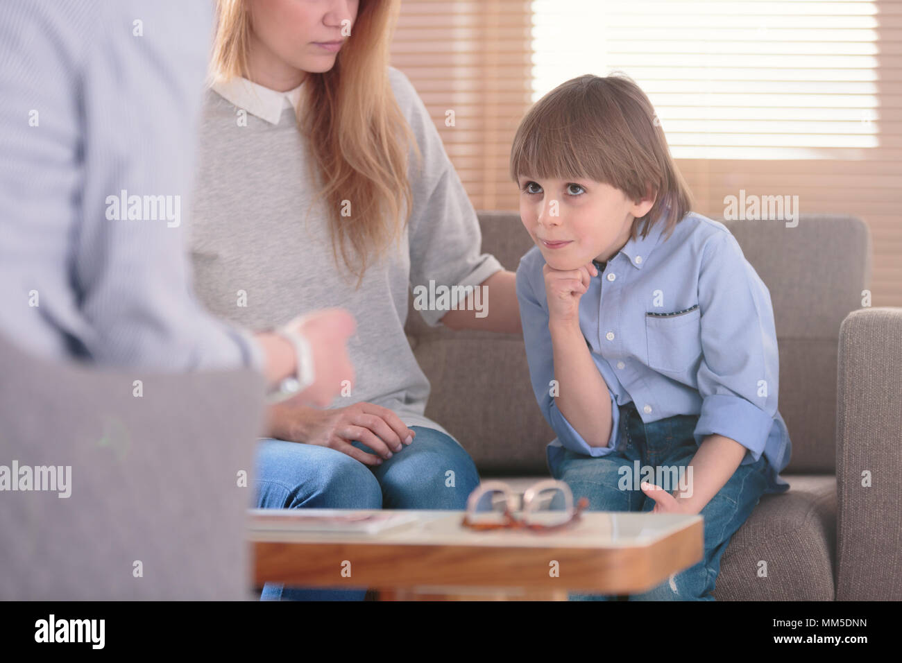 Close-up of smiling autistic boy listening to a counselor during therapy Stock Photo