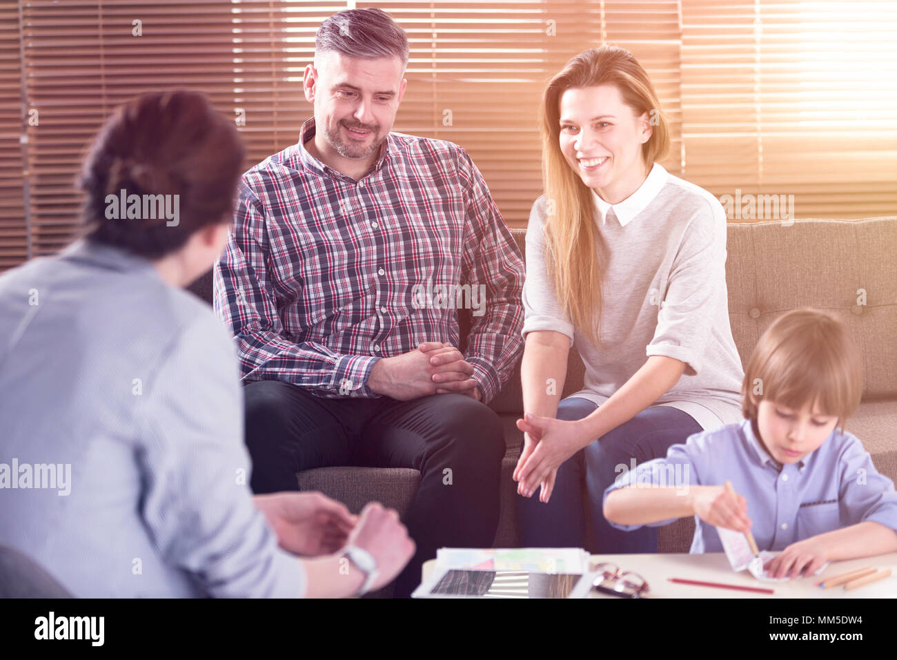 Happy family talking with their son's teacher in the office Stock Photo