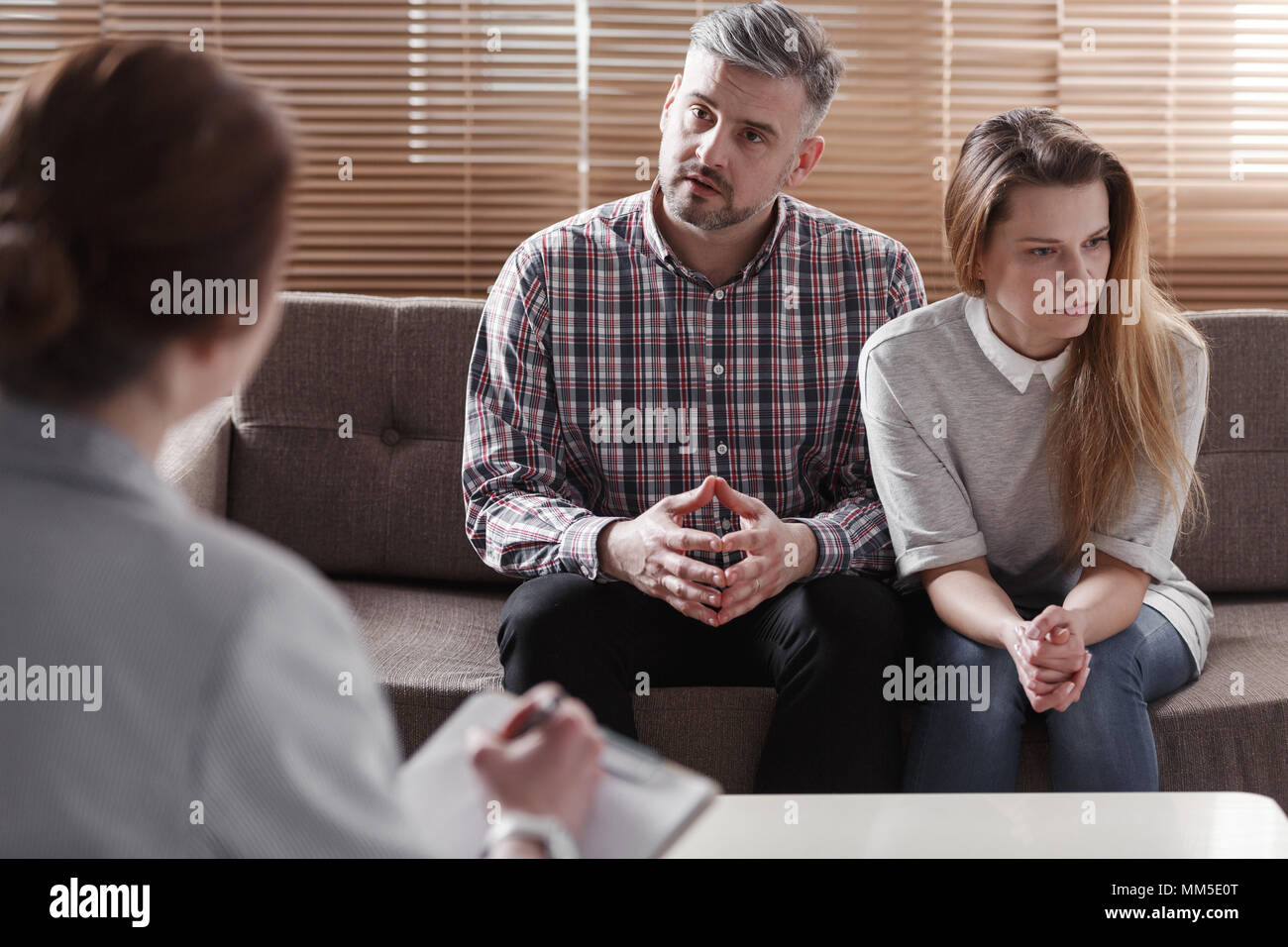 Depressed woman and husband talking with therapist for couples Stock Photo