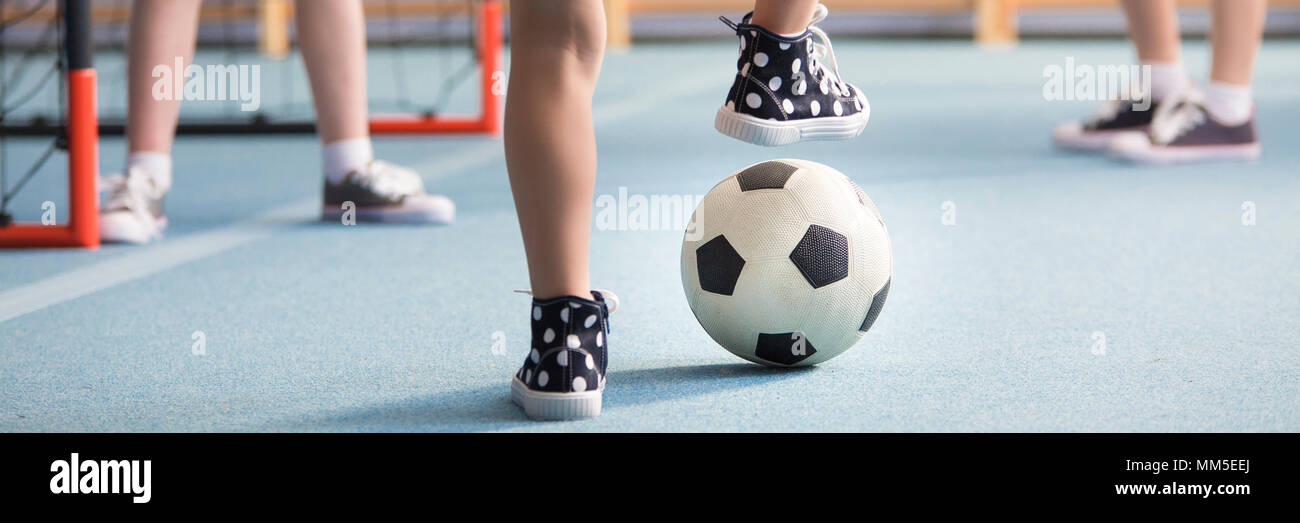 Close-up of kid in sneakers playing football at school Stock Photo