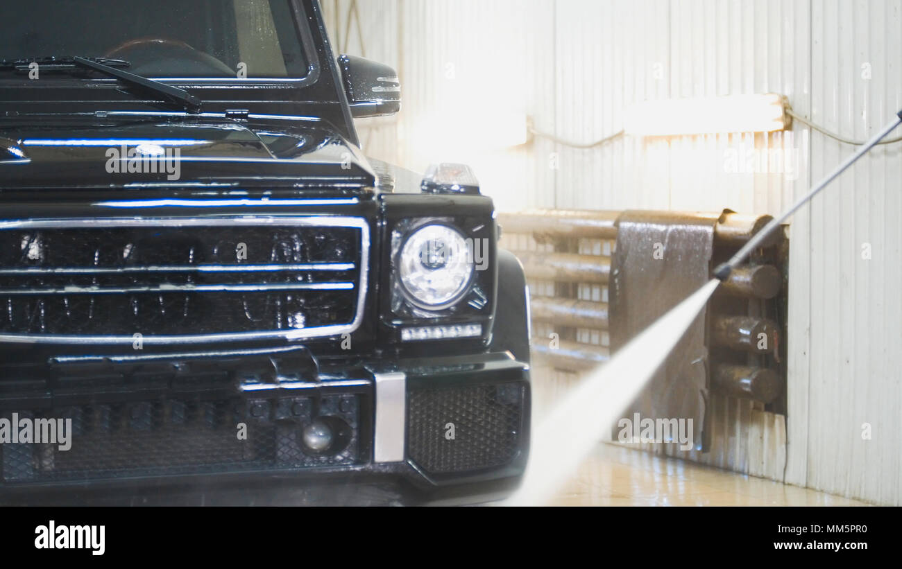 Washing the SUV car in the suds by water hoses in auto service