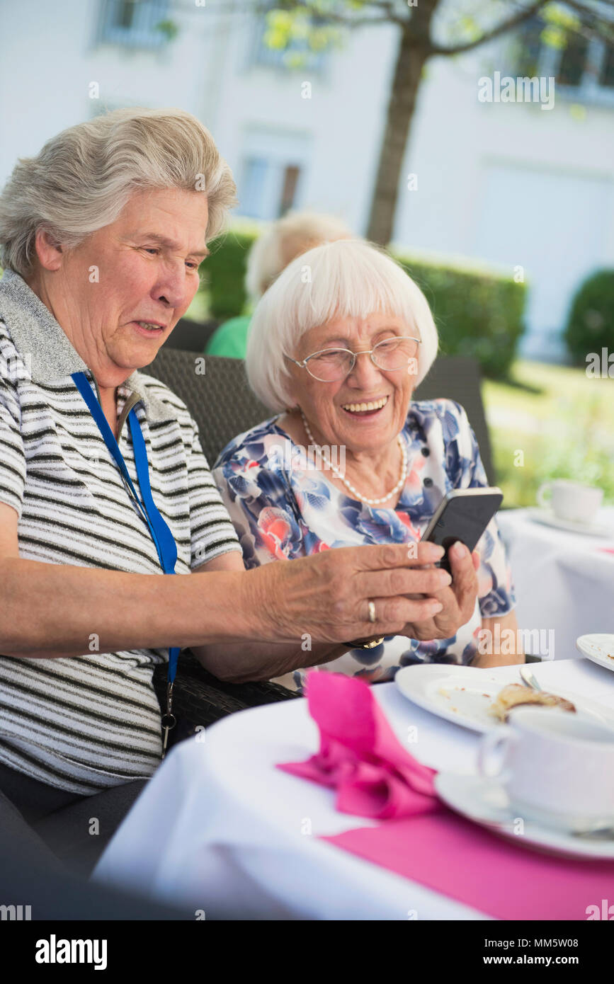 Senior women laughing and looking at smartphone Stock Photo