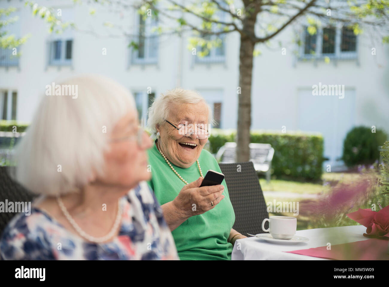 Senior woman laughing and using smartphone Stock Photo