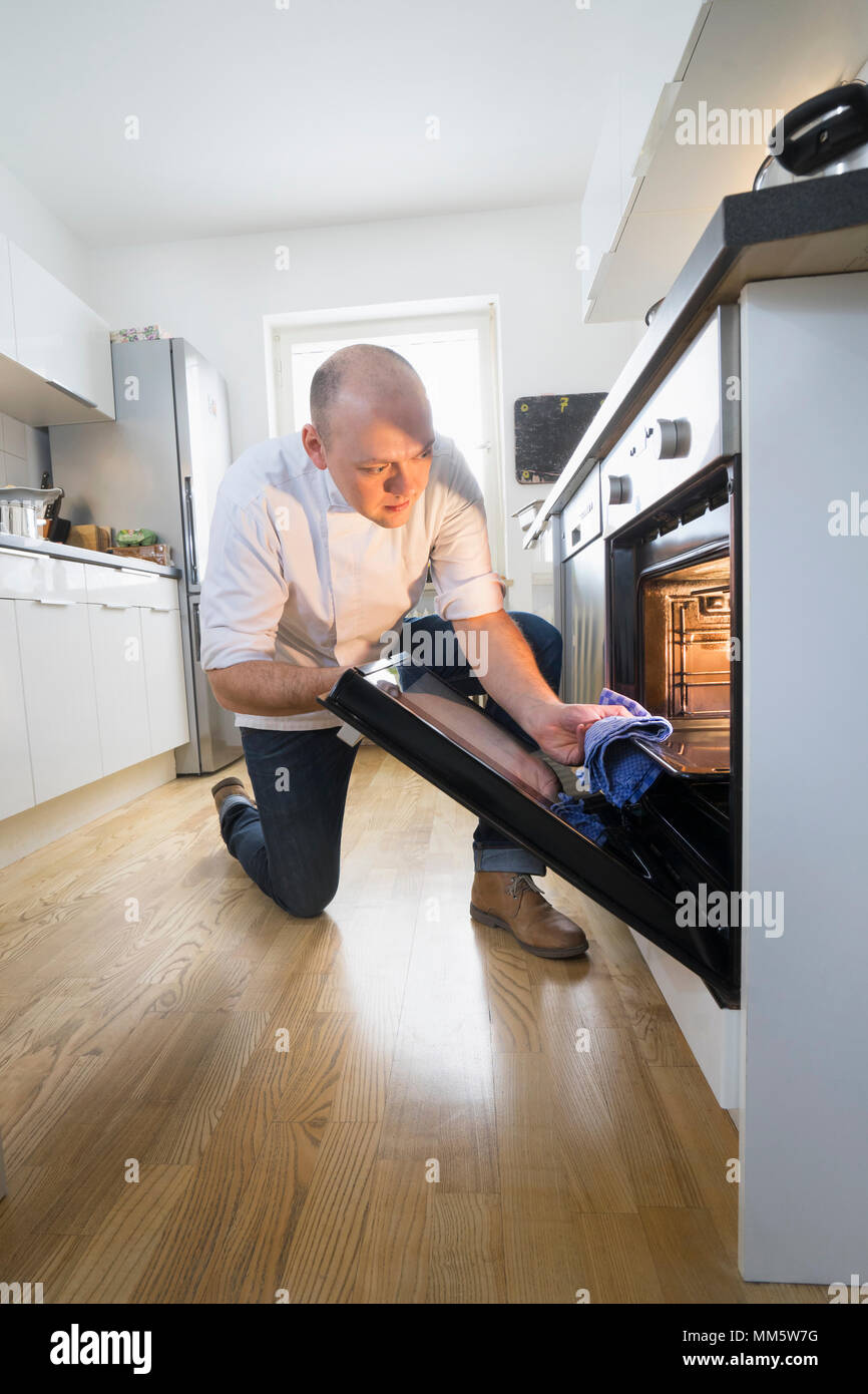 Chef removing tray from oven in private kitchen Stock Photo Alamy