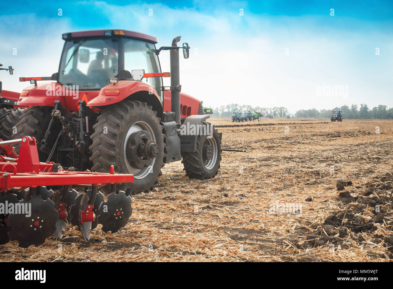 Red tractor working in a field on a bright sunny day. The concept of ...