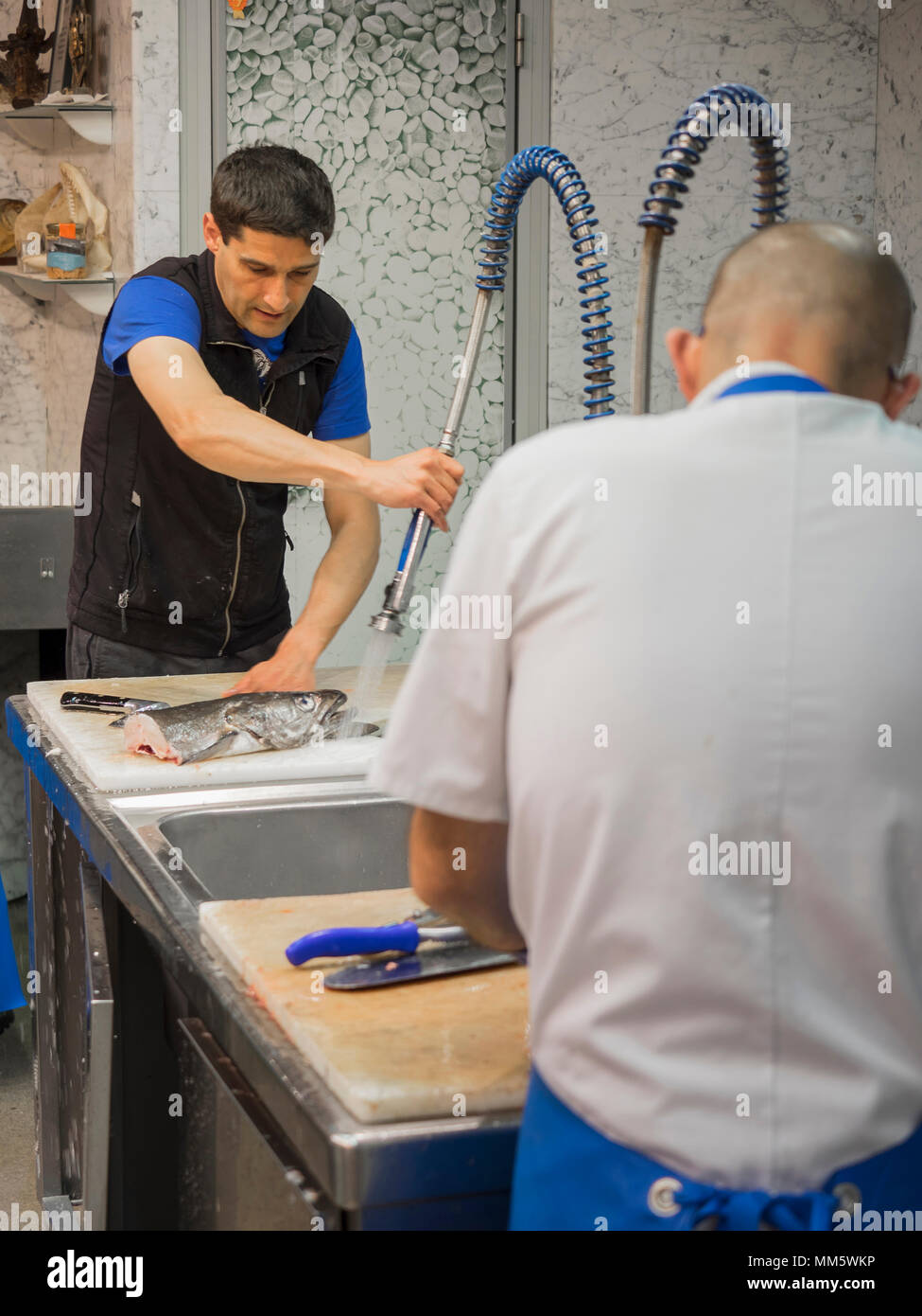 Man cleaning fish under running water Stock Photo