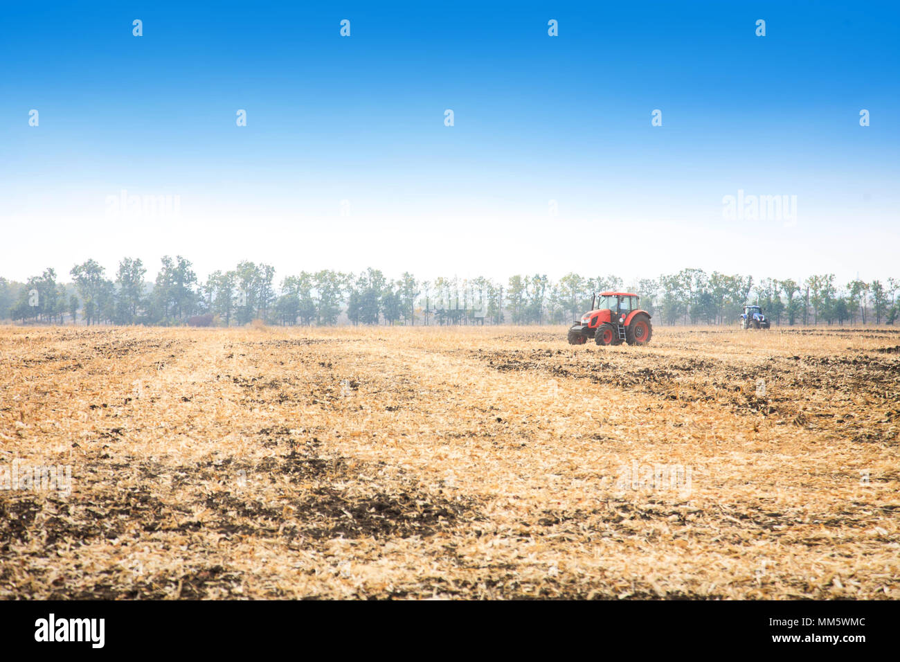 Modern red tractor in the field on a bright sunny day Stock Photo - Alamy