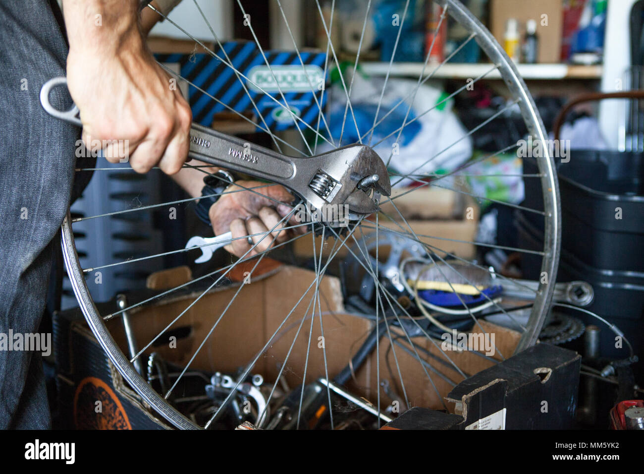 Close up on the hands of a man repairing a bicycle wheel with a wrench in rural France. Stock Photo