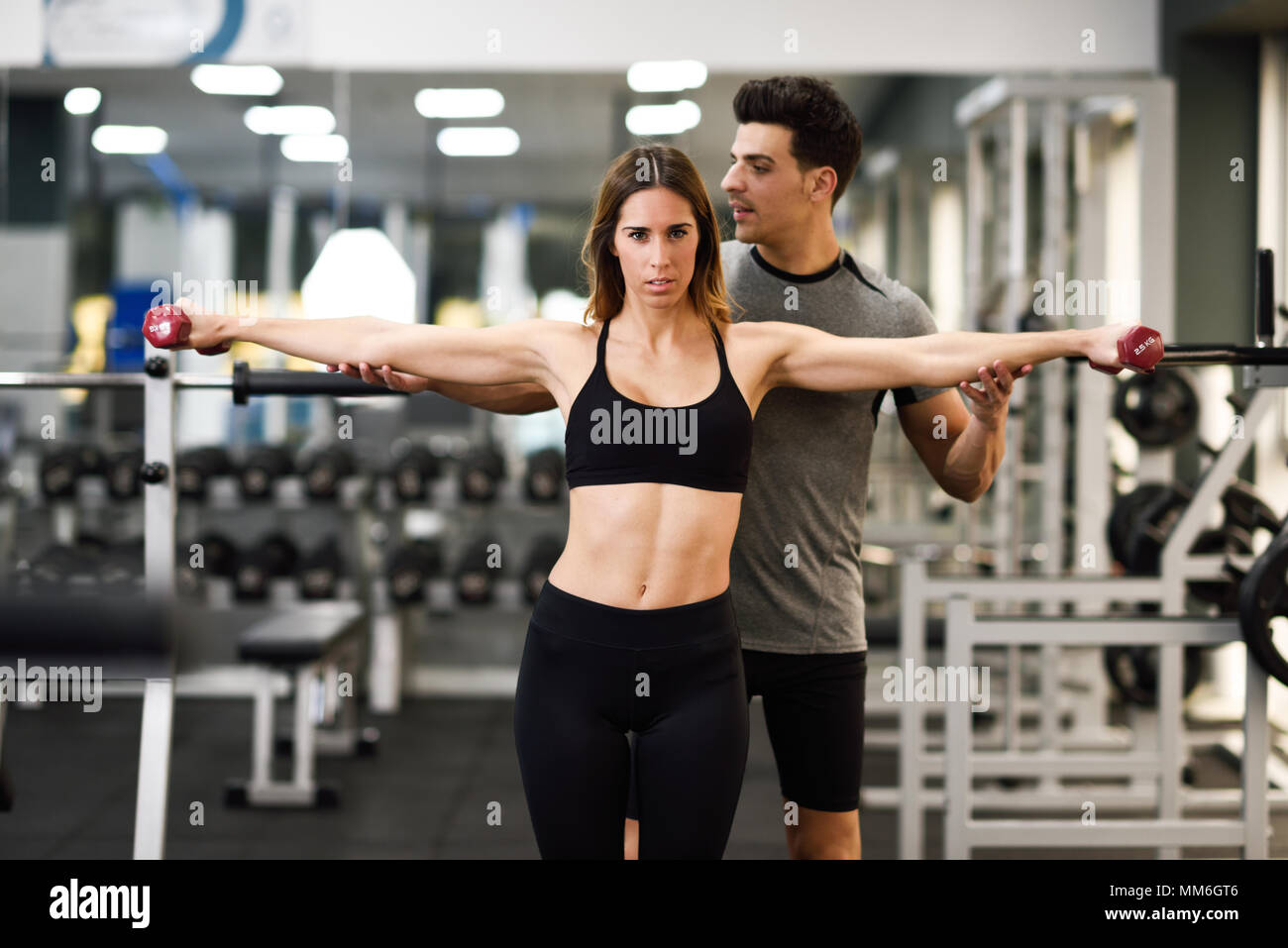 Personal trainer helping a young woman lift dumbells - a Royalty Free Stock  Photo from Photocase
