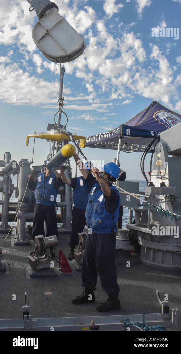 LOS ANGELES (SEPT. 8, 2017) Sailors attached to Avenger-class mine countermeasure ship USS Champion (MCM 4) use tending lines to steady the Klein 5,000, a side-scan sonar device used to survey the ocean floor, as it is lowered into the water by an articulating crane during launch operations on the Champion fantail while off the coast of Southern California. The evolution allowed the Champion to use sonar technology in order to develop an understanding of the seabed topography.  (U.S. Navy photo by Mass Communication Specialist 2nd Class Curtis D. Spencer) Stock Photo