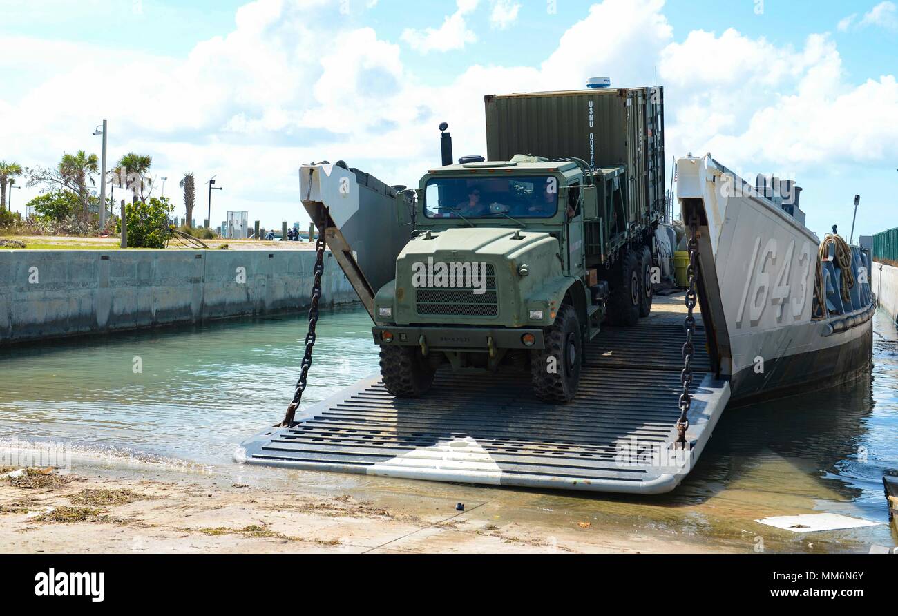 KEY WEST, Fla. (Sept. 12, 2017) Boatswain’s Mate Seaman Petir Abdal, of Northville, Michigan, directs a Medium Tactical Vehicle Replacement (MTVR), attached to Amphibious Construction Battalion (ACB) 2, up the ramp of Landing Craft Unit (LCU) 1643, attached to Assault Craft Unit (ACU) 2, during humanitarian relief efforts following Hurricane Irma’s landfall in Key West, Florida. The Department of Defense is supporting Federal Emergency Management Agency, the lead federal agency, in helping those affected by Hurricane Irma to minimize suffering and as one component of the overall whole-of-gover Stock Photo