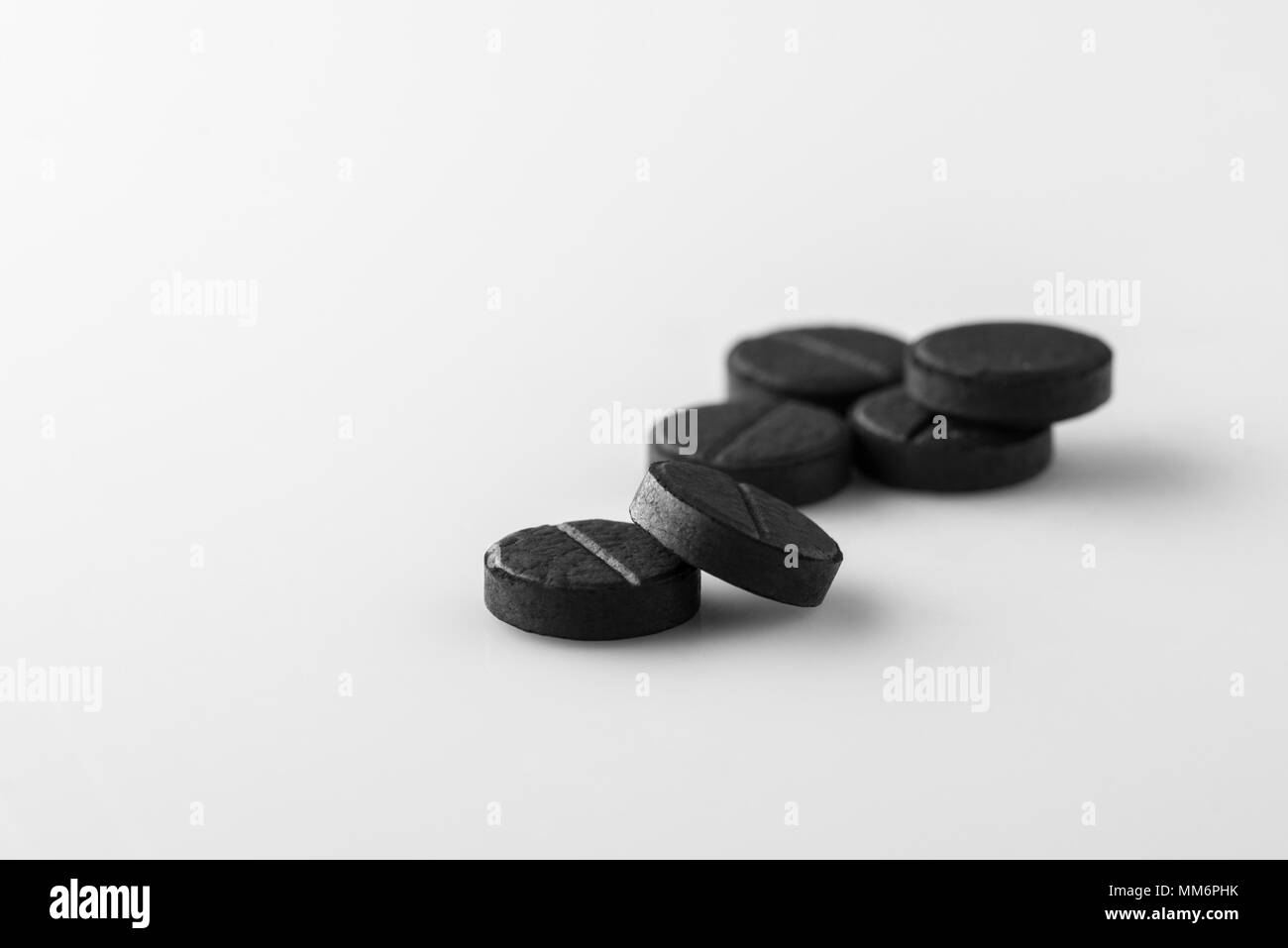 several black medical activated charcoal pills on white background.  Isolated Stock Photo - Alamy