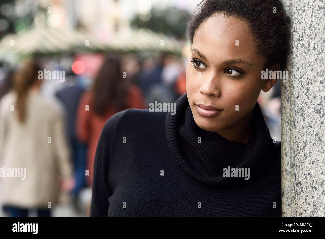 Young black female standing in an urban street. Mixed woman wearing poloneck sweater and skirt. Stock Photo