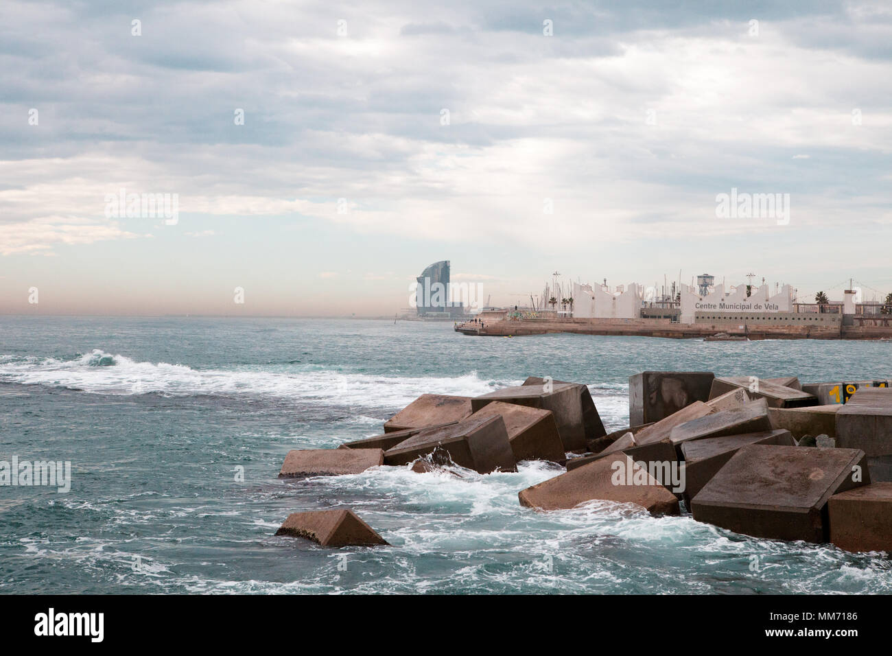 Photo from the sea wall of Llacuna, Barcelona, Spain, in the back ground the Hotel W, in the foreground concrete blocks in the mediterranean water. Stock Photo