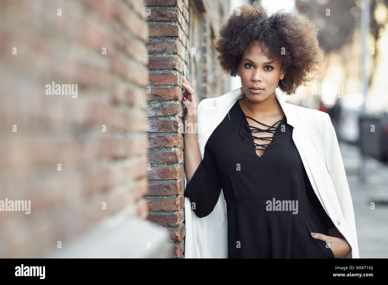 Young Black Woman With Afro Hairstyle Standing In Urban Background