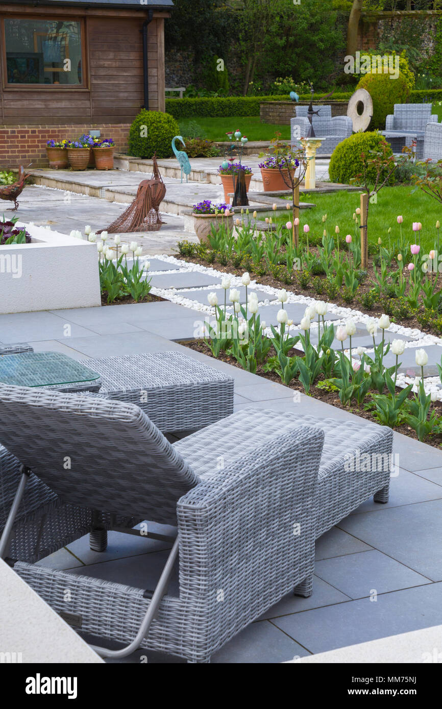 Overview of contemporary patio seating area and Tulip beds, looking towards the garden. Credits: Design by Zinnia Garden Design. Construction by 4 Lif Stock Photo