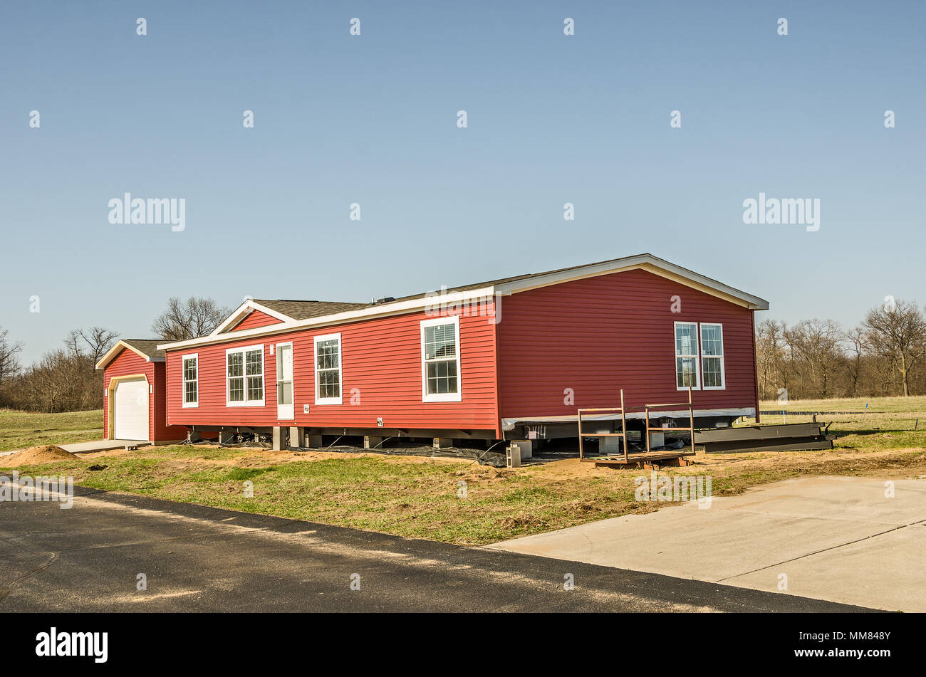 New manufactured home with red vinyl siding and windows with white lineals Stock Photo