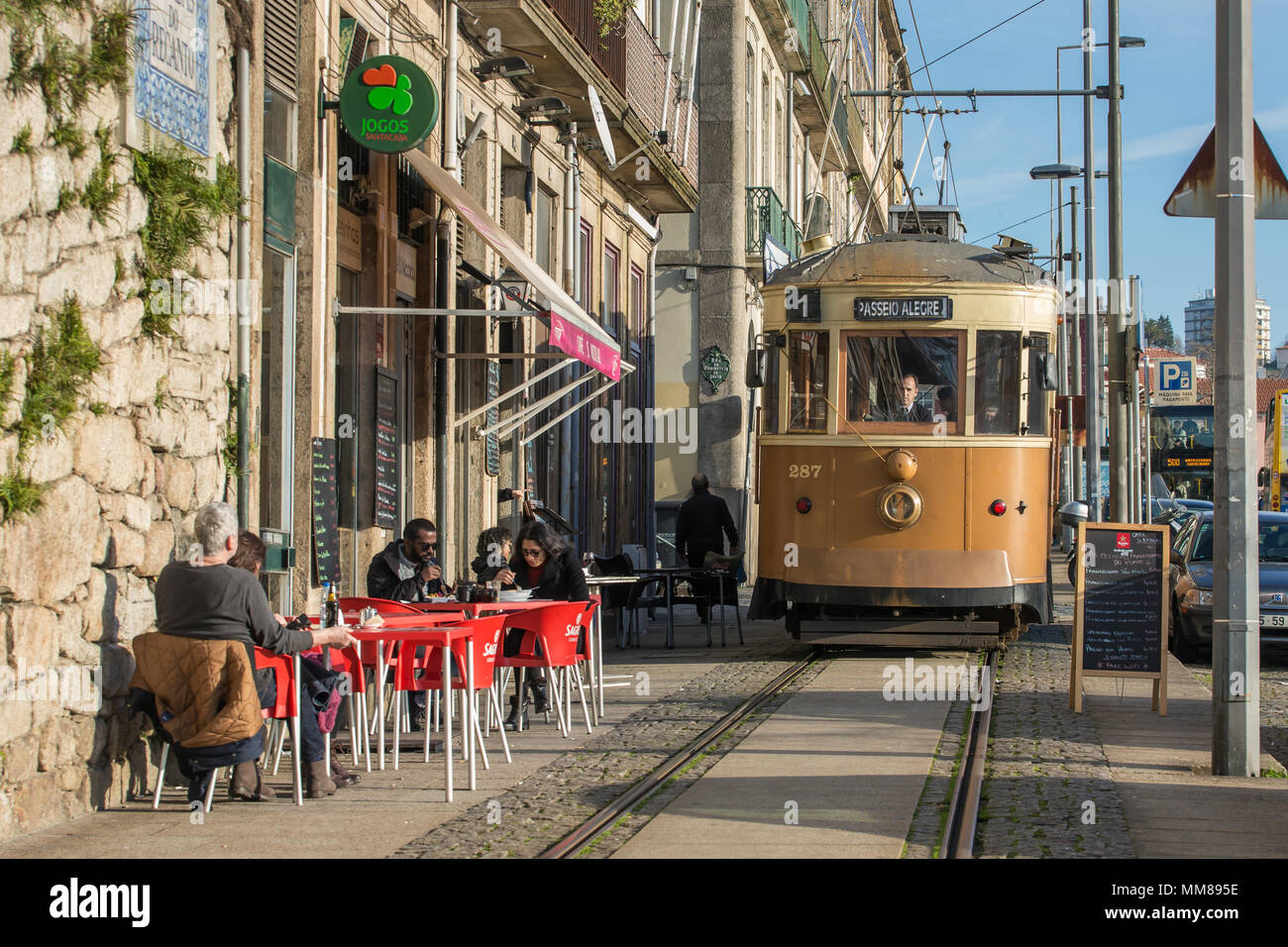 Porto, Portugal - January 19, 2018: Old tram passing by street cafe in Porto, Portugal. Stock Photo