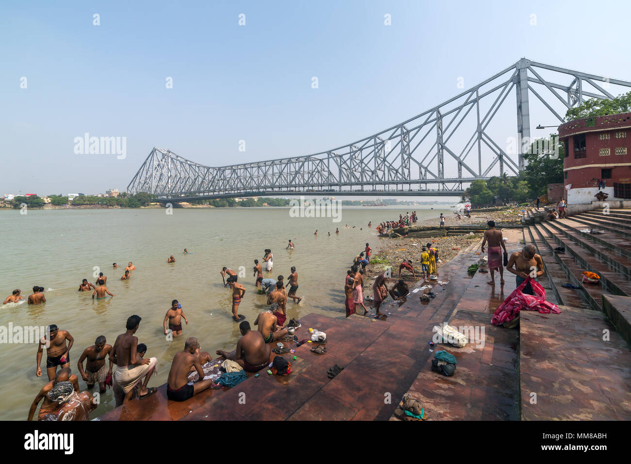 Kolkata, India - April 12, 2017: Unidentified indian people taking bath in Hooghly river with a Howrah bridge on background in Calcutta, West Bengal,  Stock Photo