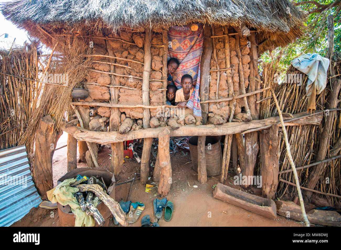 Exterior of hut with thatched roof with three young Zambian boys