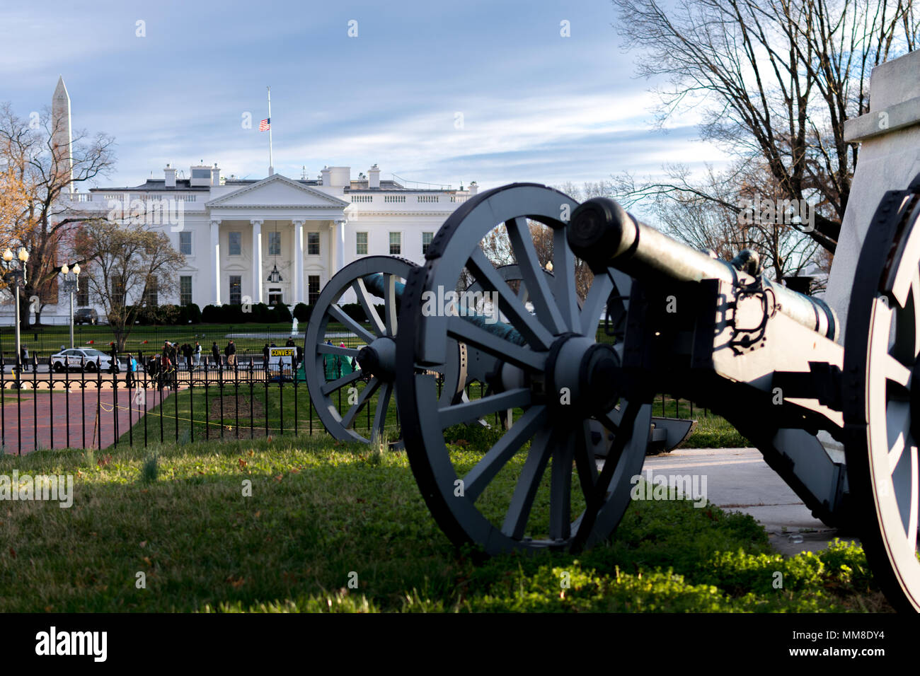 Cannon in Lafayette square in front of White House on windy blustery day, with American flag at half mast and Washington monument in background Stock Photo
