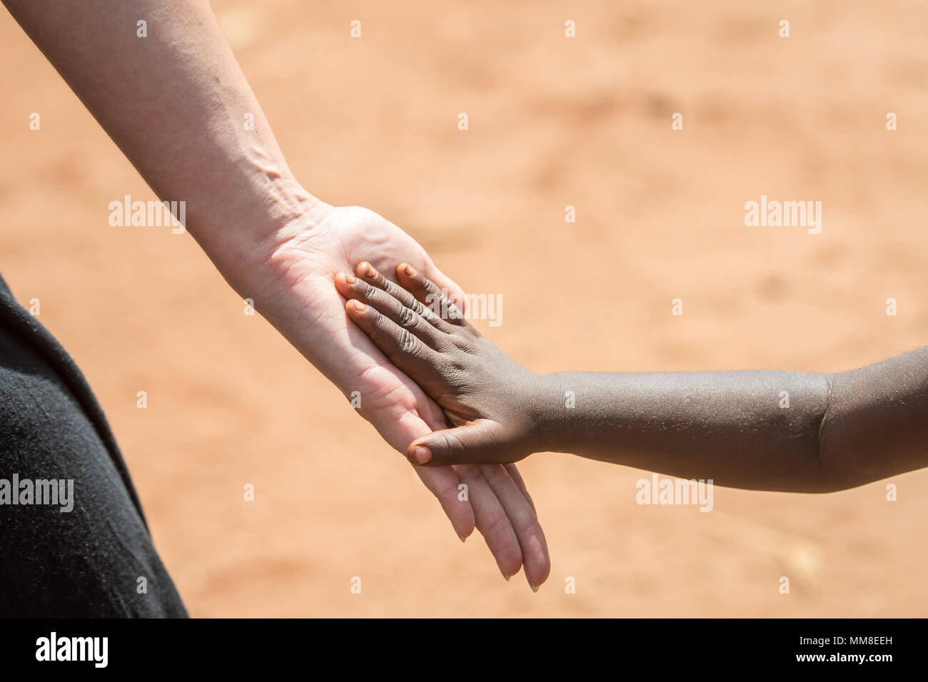 Hand of young Zambian child lightly placed against adult Caucasian woman, Mukuni Village, Zambia Stock Photo