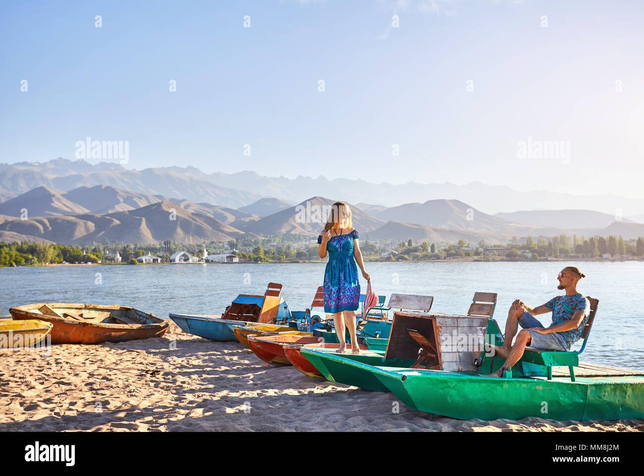 Happy couple on the old school green boat on the beach of Issyk Kul Lake in Kyrgyzstan Stock Photo
