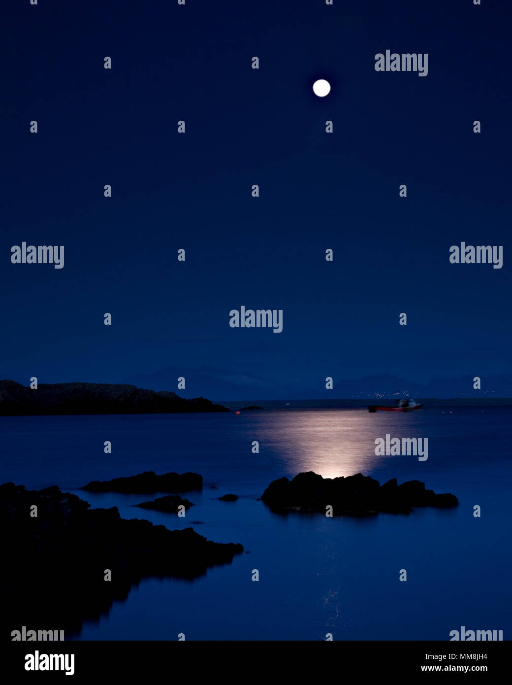 Full moon reflecting in the sea at night at Rhoscolyn, Anglesey, North Wales Stock Photo