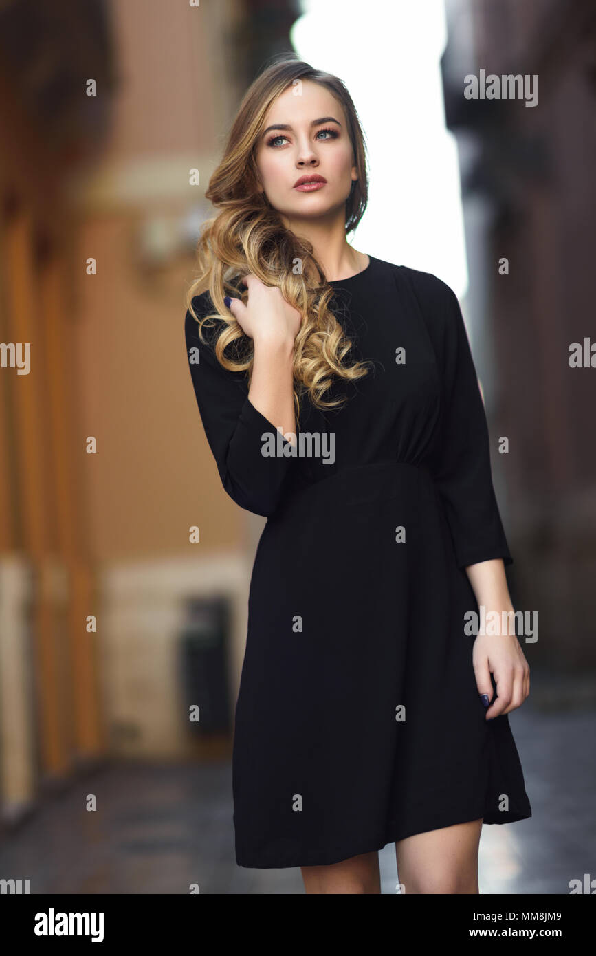 Blonde woman in urban background. Beautiful young girl wearing black elegant dress standing in the street. Pretty russian female with long wavy hair h Stock Photo - Alamy Blonde woman in urban background. Beautiful young girl wearing black elegant dress standing in the street. Pretty russian female with long wavy hair h Stock Photo - Alamy