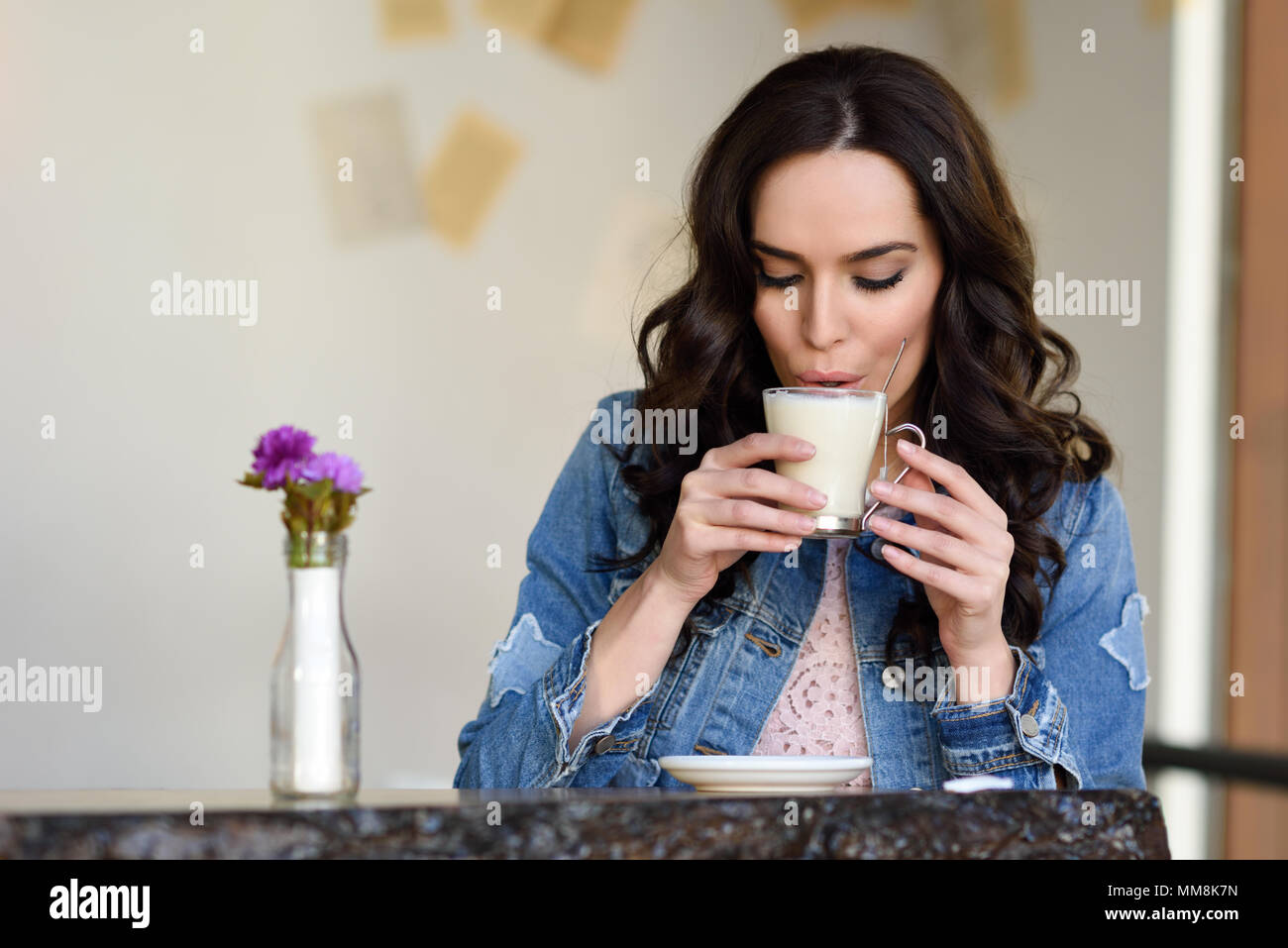 Young woman sitting indoor drinking coffee. Cool young modern caucasian female in her 20s. Cafe city lifestyle. Stock Photo