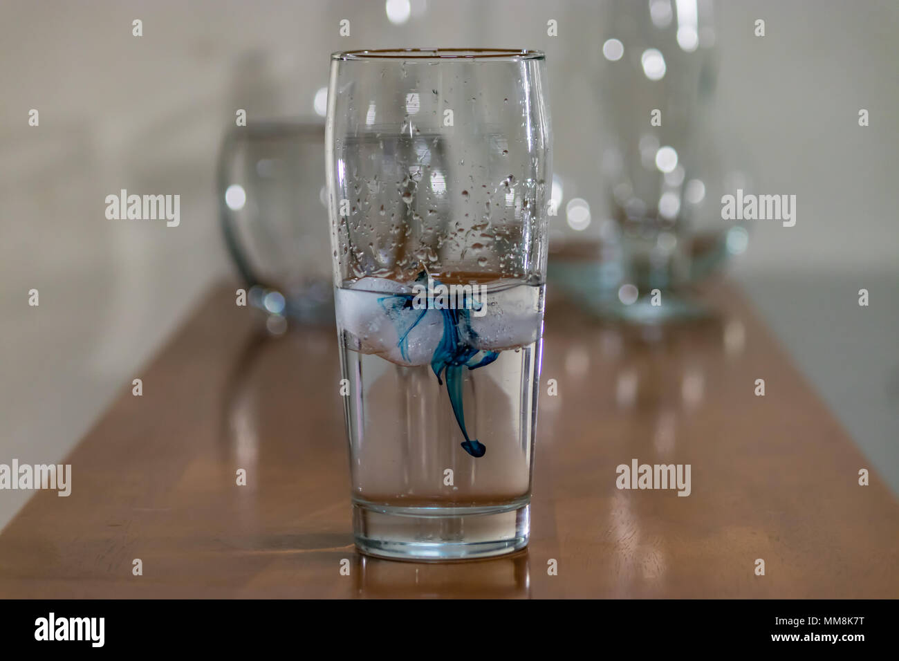blue ink in water glass on table Stock Photo