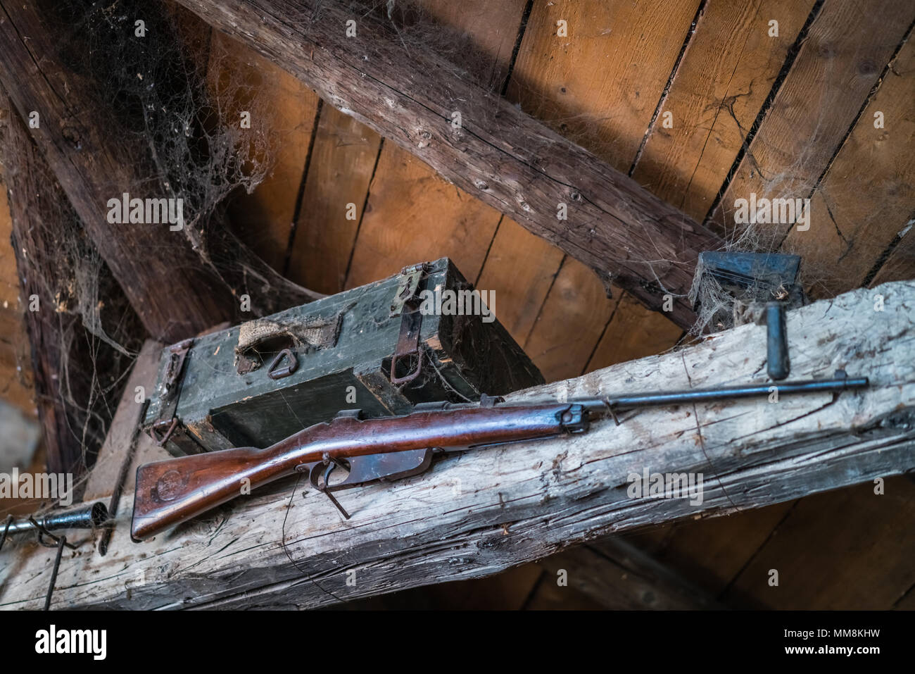 Old hunting rifle hanging on a wooden beam as display in an old farmhouse building Stock Photo